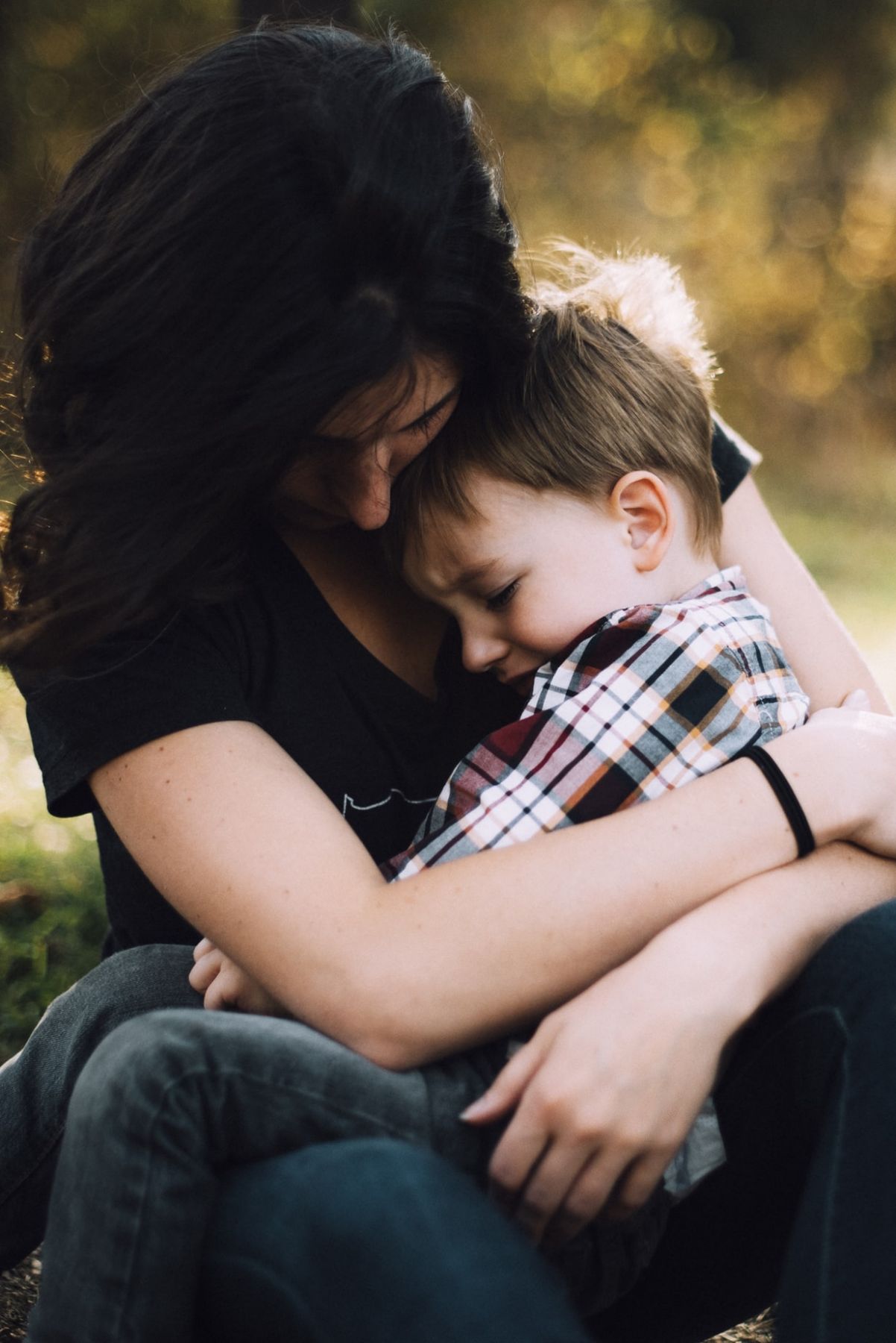 dark haired woman hugs small boy in plaid shirt