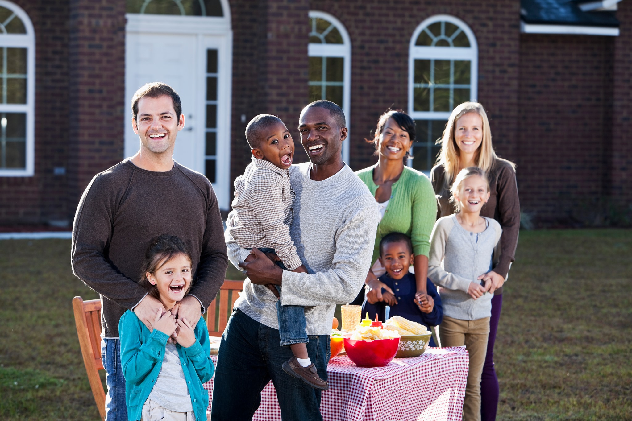 multiracial families and neighbors smiling at outdoor picnic
