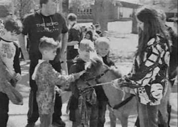 small group of young boys pet a bridled mini horse held by a woman