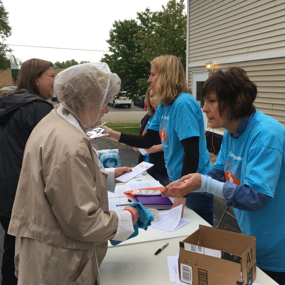 volunteers pass out information at start of fundraising 5k and walk