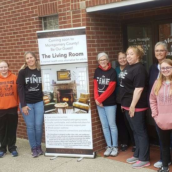 group of people pose with Coming Soon The Living Room sign