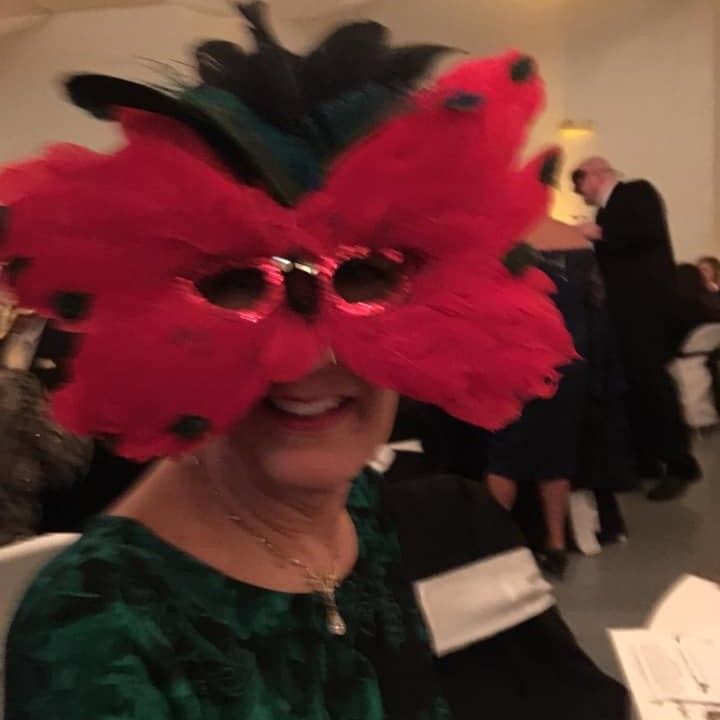 woman in pink feathered mask at hospital fundraising dinner